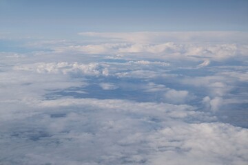 Fototapeta premium Beautiful white clouds backlit by the sun, view from the airplane window