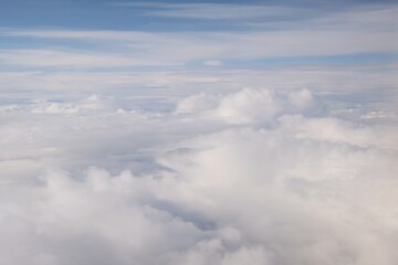 Beautiful white clouds backlit by the sun, view from the airplane window