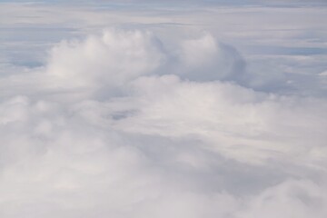 Fototapeta premium Beautiful white clouds backlit by the sun, view from the airplane window
