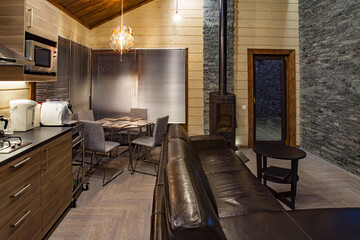 Studio interior with fireplace. A leather sofa stands in the dining room. The interior of a small country house. Apartment with fireplace. The interior of the hotel room. Loft style house.