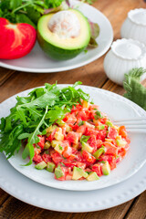 salad with avocado, tomato and red fish with arugula, selective focus