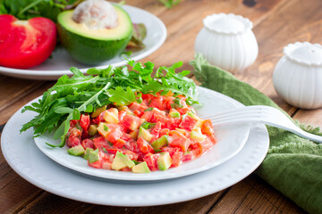 salad with avocado, tomato and red fish with arugula, selective focus