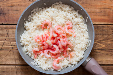 Fototapeta na wymiar Step-by-step preparation of shrimp risotto, step 5 - adding peeled shrimp, top view, selective focus