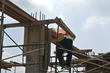 Naklejka premium MALACCA, MALAYSIA -JULY 12, 2016: Construction workers fabricating timber formwork at the construction site in Malacca, Malaysia. The formwork was mainly made from timber and plywood. 