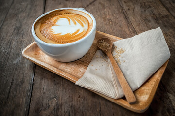 Cup of cappuccino coffee on wooden plate and brown sugar in spoon. Food background in vintage style
