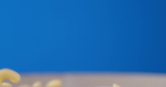 Dry pasta cavatappi falls on the table.