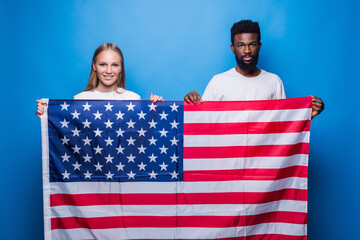 African man and caucasian woman holding american flag isolated on blue background