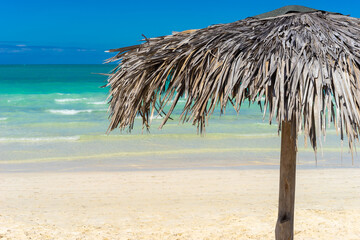 Fototapeta na wymiar Cuba. Beach. A canopy of palm branches. Beach umbrella made of palm leaves. Umbrella on the background of an exotic beach. Shadow. Island Cuba Tourism. Caribbean landscape. Sand beach.