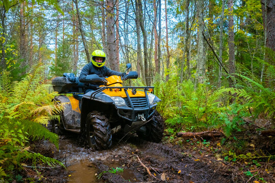 Man on a yellow ATV. A man riding a quad bike in the forest. ATV rides through the mud. Extreme off-road driving. Concept - off-road ATV race. Concept - sale of quad bike. Extreme sport