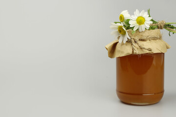 Honey in a jar covered with paper and wild flowers