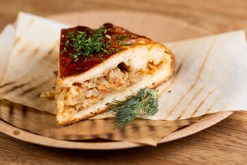 pie with stewed cabbage and carrots sprinkled with herbs on a disposable plate