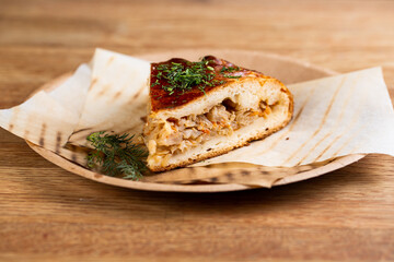 pie with stewed cabbage and carrots sprinkled with herbs on a disposable plate