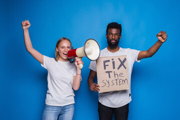 Young caucasian woman with megaphone and African man holding a cardboard poster with the message...