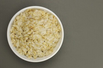Bowl of oats porridge on a gray background. Healthy breakfast