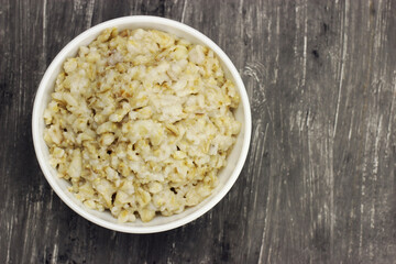 Bowl of oats porridge on a gray background. Healthy breakfast