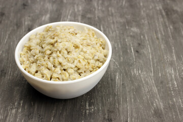 Bowl of oats porridge on a gray background. Healthy breakfast