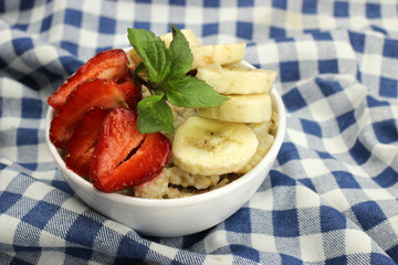 Oatmeal with strawberries, banana and mint on a checkered tablecloth
