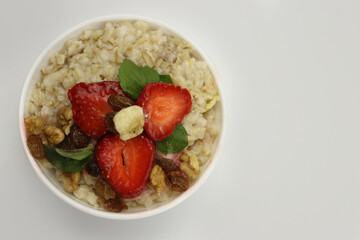 Bowl of oatmeal with a banana, strawberries and mint. The view from the top. Fresh healthy Breakfast