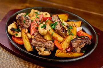 hot frying pan with potatoes, meat, peppers on stand