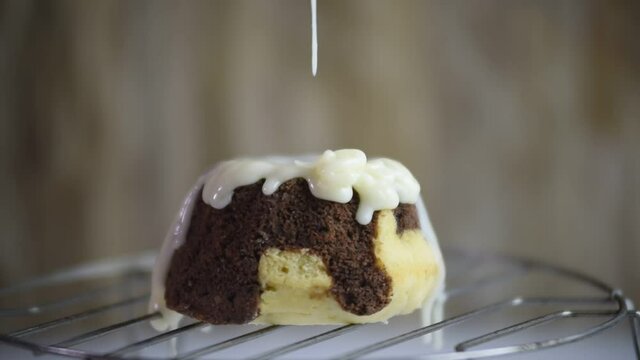 white chocolate frosting dripping onto a marbled pudding, garnished with a dripping splash