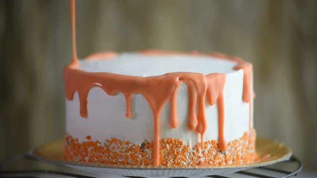 orange chocolate icing falling on a cake, decorating with a dripping splash