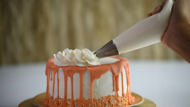 pastry hands decorating with cake and cream, a cake with orange chocolate, with white background.