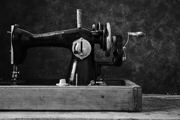 Old, retro, vintage sewing machine on a dark background of an abstract wall.