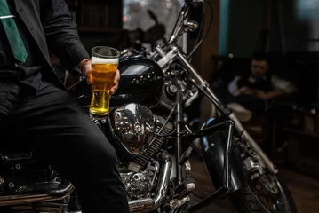 Photo sur Plexiglas Moto Motard assis sur une moto personnalisée avec un verre de bière artisanale brillante. Vélo chromé