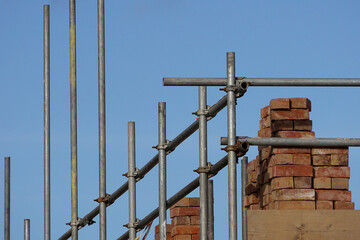 Fototapeta premium Scaffolding and bricks on a building site against a blue sky