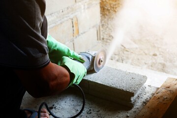 man bricklayer is cutting cement brick block with Small cutter machine for wall construction in new...