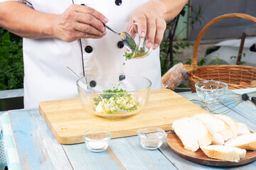 Chef putting minced parsley to bowl for cook garlic bread