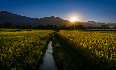 Sun setting behind hills, mountains, canals and paddy fields in a valley in Nepal. View of Rampur, Palpa Nepal.
