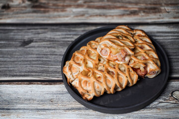 Close up croissant pizza stuffed sausage, ham and bacon on wooden table.