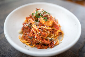 A Pasta/Spaghetti with shrimp and cheese that served in the white luxury dish, placed on wooden table. Italian food and special dish photo. Select focus on the food surface.