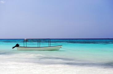 White sandy beach with sea and boat.Tropical seashore scenery. Exotic island vacation