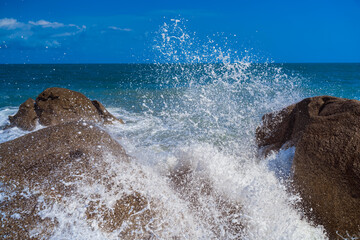 Sea water splashes. The wave rolls over the rocks and breaks on them.
