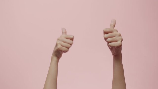 Close up of Woman's hands showing and making thumb up sign isolated on a pink studio background with copy space for place a text, message for advertisement, and promotional