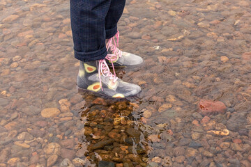 A girl in rubber boots in the water.