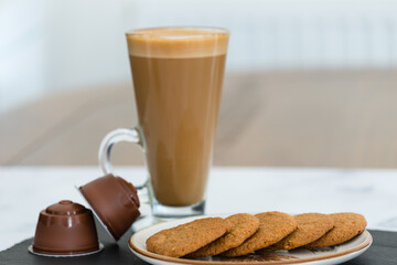 Tall latte in a Glass and Five Coffee and Ginger Biscuits on a Plate Typical Cafe at Home During Covid.