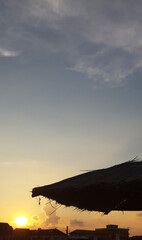 Sunset and a reed umbrella on a beach