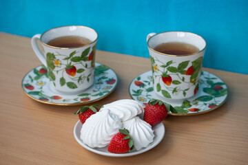 two cups of tea and marshmallow with strawberries