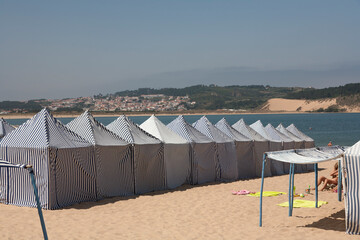 blue and white tents on beach. These are hired and use for shade and changing. The Portuguese name is barraca
