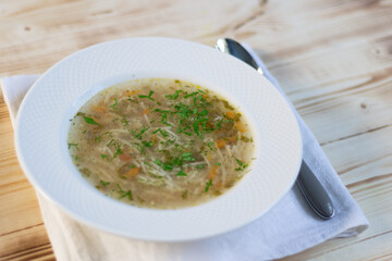 Spaghetty soup lapsha in white plate with spoon on wooden table