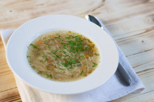 Spaghetty soup lapsha in white plate with spoon on wooden table