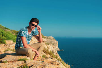 Fototapeta premium Young man sitting at the sea on the horizon