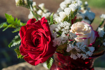 red glass vase flower arrangement with large red rose amid white flowers