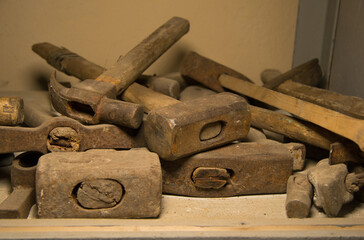 Many iron hammers of different shapes lie in the closet. Large and small hammers with wooden handles