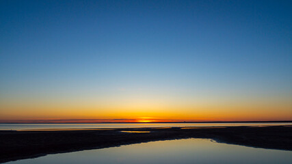 Colorful sunset on the beach. The sky reflected in the water.
