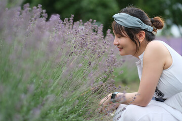 One beautiful Asian young woman squatting at lavender bush. Smell the flowers and smile