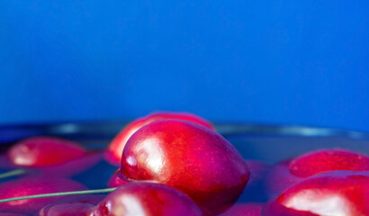 Bright cherry berries in water on a blue background